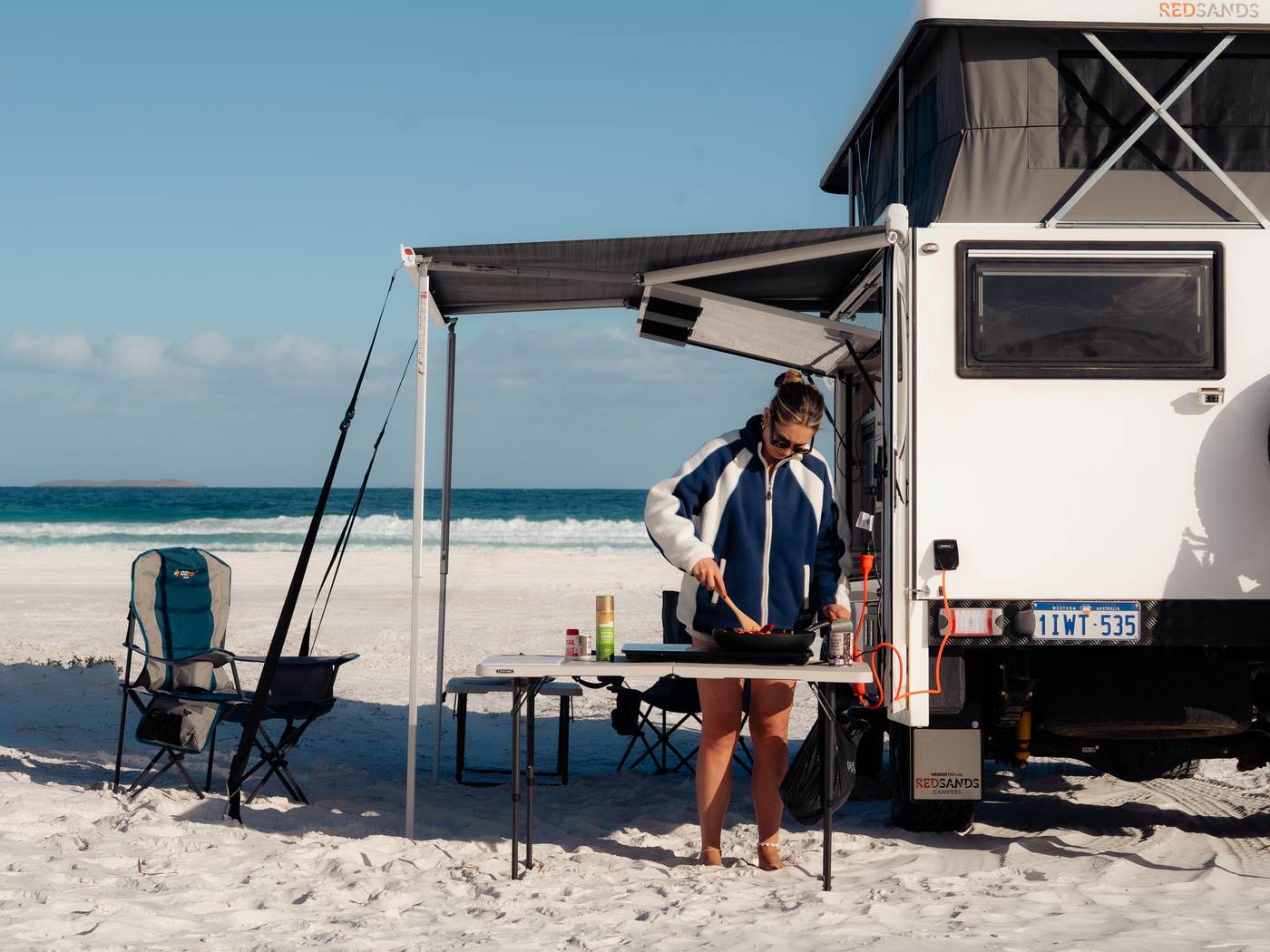 Gemütliches Frühstück unter der Wohnwagenmarkise an einem weißen Sandstrand