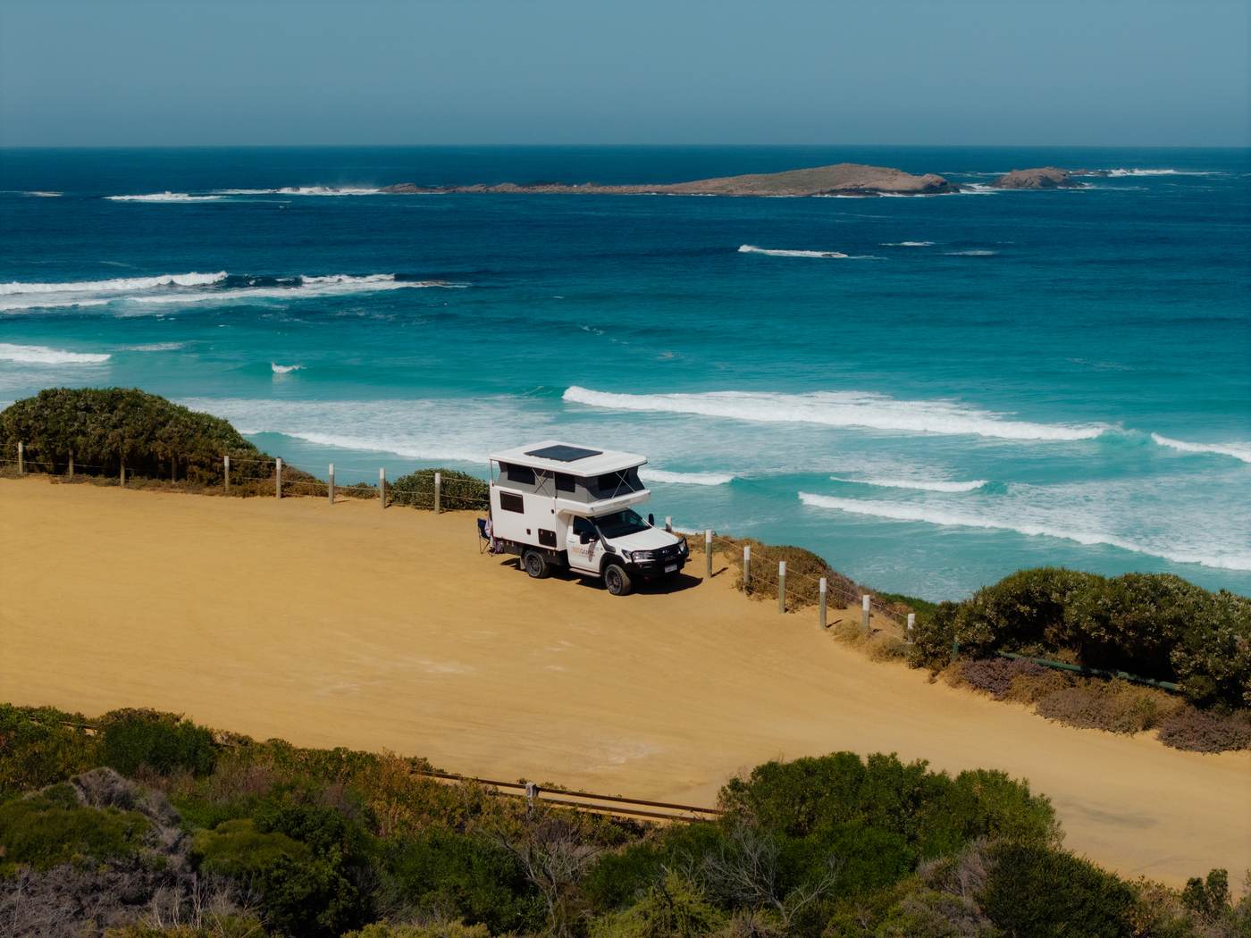 Camper über einem türkisblauen Surfstrand geparkt